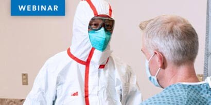 health care provider wearing full body suit, a particulate respirator and eye goggles talking with patient in mask
