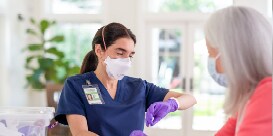 clinician using PPE and providing home care for a patient
