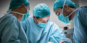 Three surgeons operating on a patient
